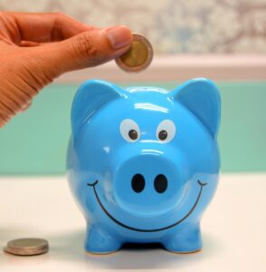 putting a coin into a blue piggy bank